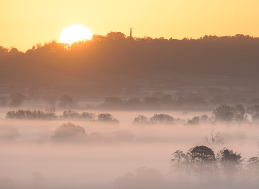 A foggy sunrise over the Compton Dundon Moor and the Hood Monument on the Somerset Levels